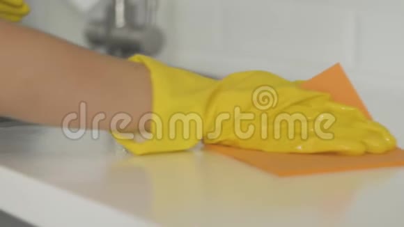 一位戴着黄手套的家庭主妇用抹布擦桌子视频的预览图