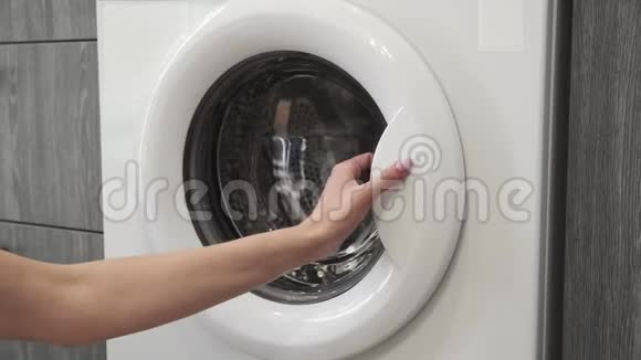 女性手带结婚戒指把白色的衣服放在洗衣机里去装洗衣机把衣服装上洗衣机视频的预览图