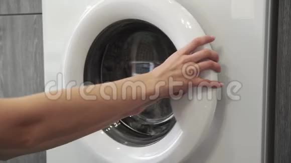 女性手从洗衣机里拿着绿色SWEATER去装洗衣机把衣服装进洗衣机负荷视频的预览图