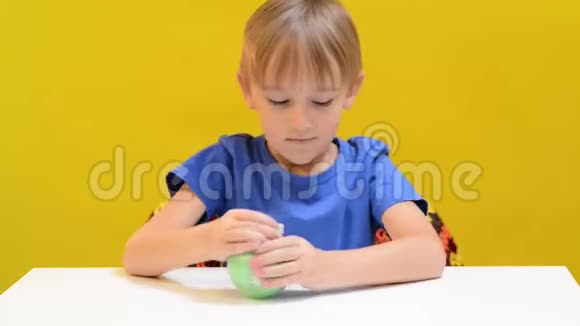 有趣的男孩在桌子上玩时髦的黏液玩具孩子玩得开心享受黏液抗压力视频的预览图
