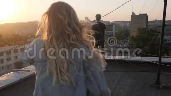 一个女孩跑到她的爱人的屋顶上一个古老的苏联房子日落视频的预览图