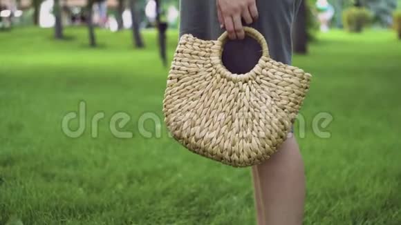年轻的女人带着手工制作的时尚草包在夏季公园散步环保袋视频的预览图