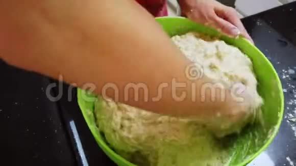 年轻的女人在家里用绿色的碗揉面包面团在隔离或隔离的情况下制造自己食物的人的概念视频的预览图