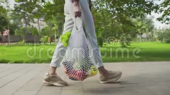无法辨认的女人拿着带蔬菜的棉网购物袋在夏季公园散步视频的预览图