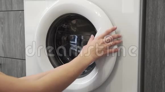 带结婚戒指的女性手把JEANS放进洗衣机里去装洗衣机把衣服装上洗衣机视频的预览图