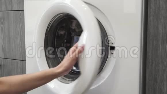 女性的手从洗衣机里拿JEANS去装洗衣机把衣服装进洗衣机穿上衣服视频的预览图