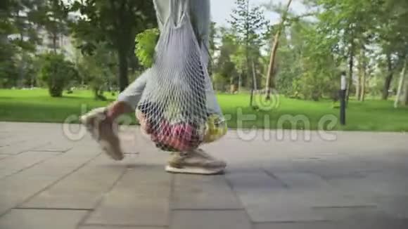 无法辨认的女人拿着带蔬菜的棉网购物袋在夏季公园散步视频的预览图