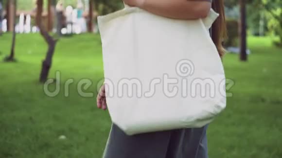 小女孩拿着白色纺织生态袋在夏季公园散步视频的预览图