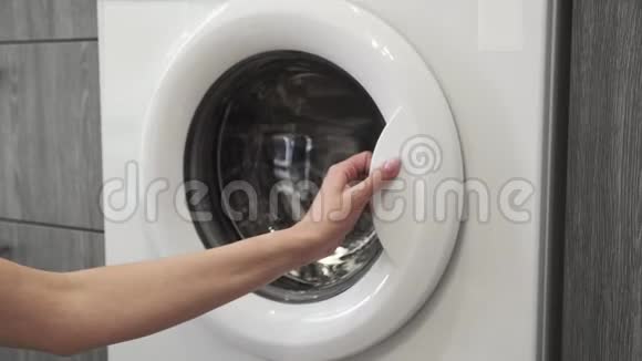 带结婚戒指的女性手把有颜色的衣服放在洗衣机里去装洗衣机把衣服装上洗衣机视频的预览图