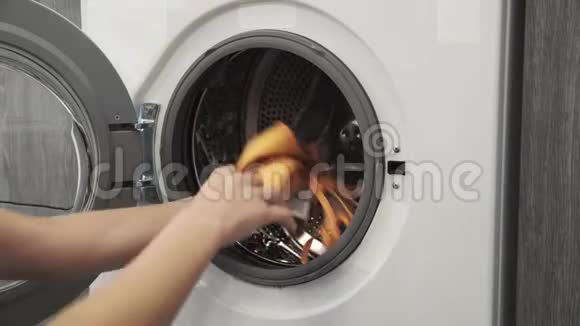 女性手把彩色的衣服放在洗衣机里去装洗衣机把衣服装进洗衣机负荷视频的预览图