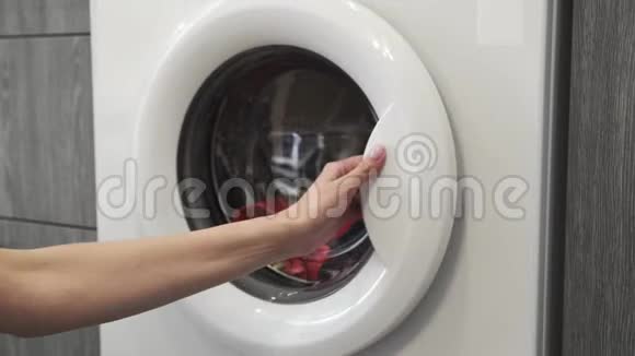 女性的手从洗衣机里拿着彩色的衣服去装洗衣机把衣服装进洗衣机负荷视频的预览图