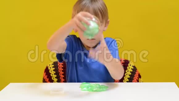 快乐的孩子玩得开心享受与黏液抗压力的黄色墙儿童在书桌上玩时髦的黏液玩具视频的预览图