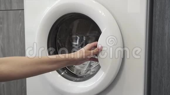 女性手从洗衣机里拿白色衣服去装洗衣机把衣服装进洗衣机负荷视频的预览图