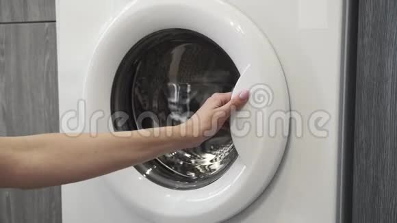 女性手把白色的衣服放在洗衣机里去装洗衣机把衣服装进洗衣机穿上衣服视频的预览图