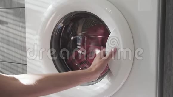女用手从洗衣机里取出粉红色的衣服去装洗衣机把衣服装进洗衣机负荷视频的预览图