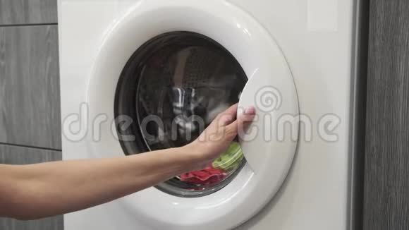 女性的手从洗衣机里拿着彩色的衣服去装洗衣机把衣服装进洗衣机负荷视频的预览图