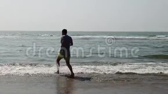 在海岸附近的海里迷人的人在海中溅水和摆姿势相机微笑的男人在玩视频的预览图