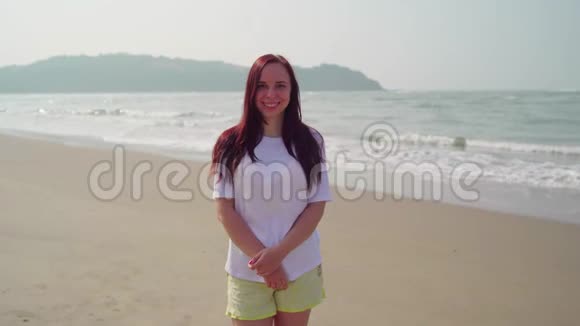 英俊的女人站在海边的沙滩上在海滨阳光明媚的日子里女游客开心地笑着视频的预览图