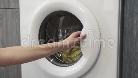 女性手从洗衣机里拿衣服去装洗衣机把衣服装进洗衣机穿上衣服视频的预览图