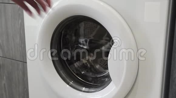 女性手把白色毛巾放在洗衣机里去装洗衣机把衣服装进洗衣机穿上衣服视频的预览图