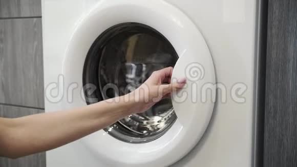 女性手把黄色的JACKET放在洗衣机里去装洗衣机把衣服装进洗衣机穿上衣服视频的预览图