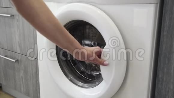 女性手把BLAKCJACKET放在洗衣机里去装洗衣机把衣服装进洗衣机穿上衣服视频的预览图