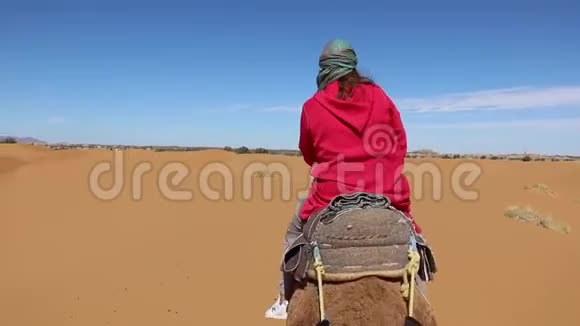 穿着粉色长袍和头巾的妇女穿过摩洛哥的埃尔格切比沙漠视频的预览图