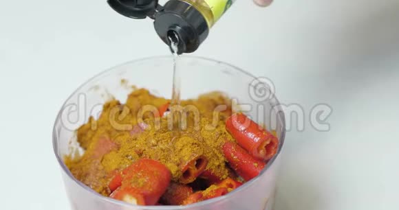 特写镜头一位厨师用切好的辣辣椒粉将白葡萄酒醋从一瓶中倒入搅拌机中用来研磨酱油视频的预览图