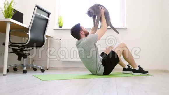 男人在家里用猫做ABS家庭运动健康生活检疫理念宠物视频的预览图