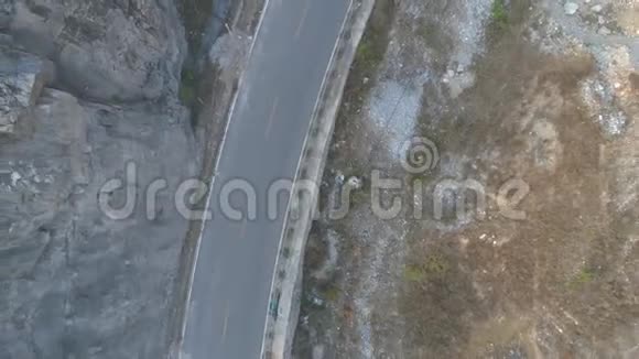白色汽车在干燥的山上行驶在一条小沥青路上的高空俯视图视频的预览图