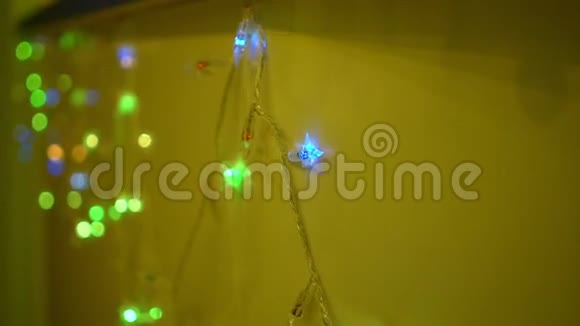 多种颜色的圣诞花环和黄墙背景灯视频的预览图