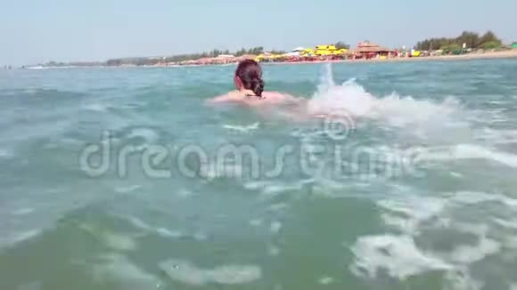 穿着黑色泳衣的年轻女子花时间在海里成年女士游向海浪视频的预览图