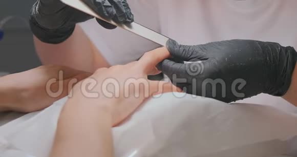 美容师在美容院用档案清洁顾客指甲视频的预览图