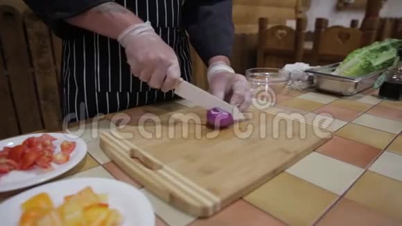 在黑板上用一个戴沙拉手套的人在厨房里切洋葱视频的预览图