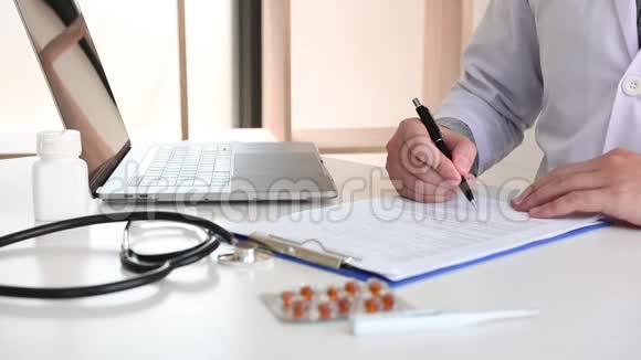 医生阅读有关病人病情报告的文件并使用笔记本电脑记录信息视频的预览图