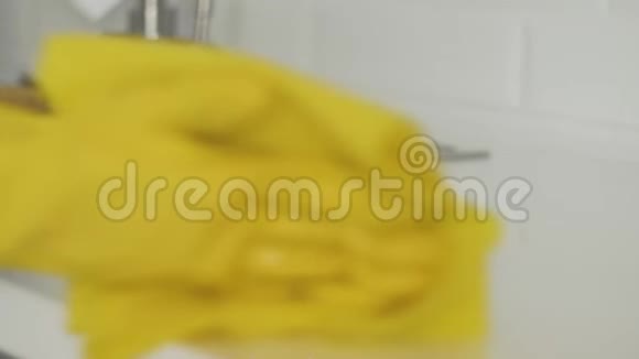 家庭主妇戴黄手套的女人用黄布擦桌子视频的预览图