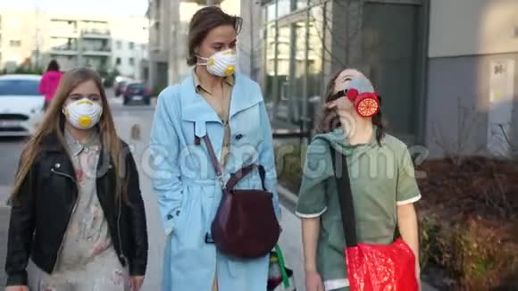 一家三口一个母亲和两个孩子一个男孩和一个女孩在一条城市街道上蒙面冠状病毒大流行视频的预览图