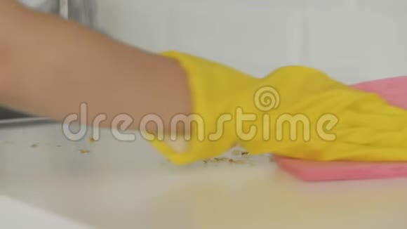 女家庭主妇戴着黄色手套用粉红色的抹布清理桌子上的碎屑视频的预览图