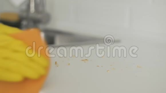 女家庭主妇戴着黄色手套用橙色抹布清理桌子上的碎屑视频的预览图