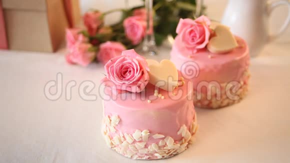女人的手在附近放了一杯咖啡上面有粉红色的小蛋糕装饰着美丽的玫瑰视频的预览图