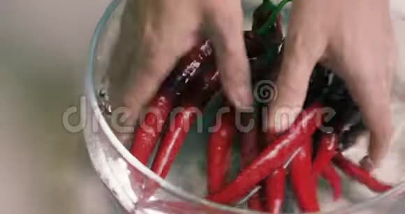 男人的手在玻璃花瓶里洗干净新鲜的红辣椒素食健康营养食品视频的预览图