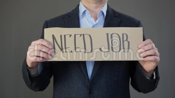 失业商人在灰色背景上持有需要工作标志的海报找工作的失业经理视频的预览图
