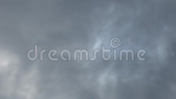 深灰色和蓝色的云在天空上迅速移动模糊的光线穿过它们太阳在阴霾中天气不好阴天视频的预览图