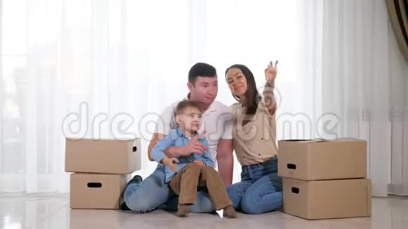 有儿子的家庭坐在地板上妻子出示新房钥匙视频的预览图