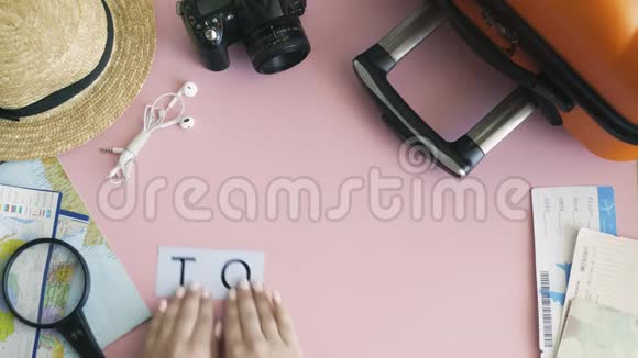 顶部的双手躺在粉红色的桌子上写着旅游视频的预览图