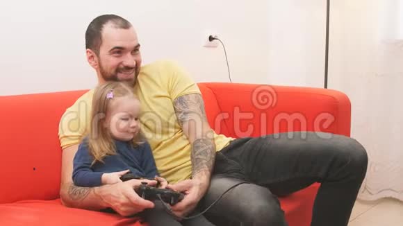 微笑的白种人的女儿和父亲玩电子游戏视频的预览图