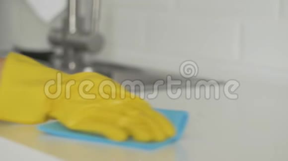 带着黄手套的家庭主妇用蓝色抹布擦桌子视频的预览图