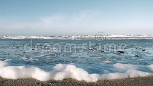 近景背景观白海泡沫堆积在强风下北海滩晴天慢动作视频的预览图