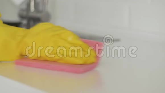 家庭主妇戴黄手套的女人用粉红色的抹布擦桌子视频的预览图