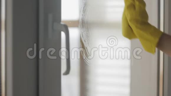 家庭主妇戴黄色手套用黄色抹布和洗涤剂清洗窗户视频的预览图